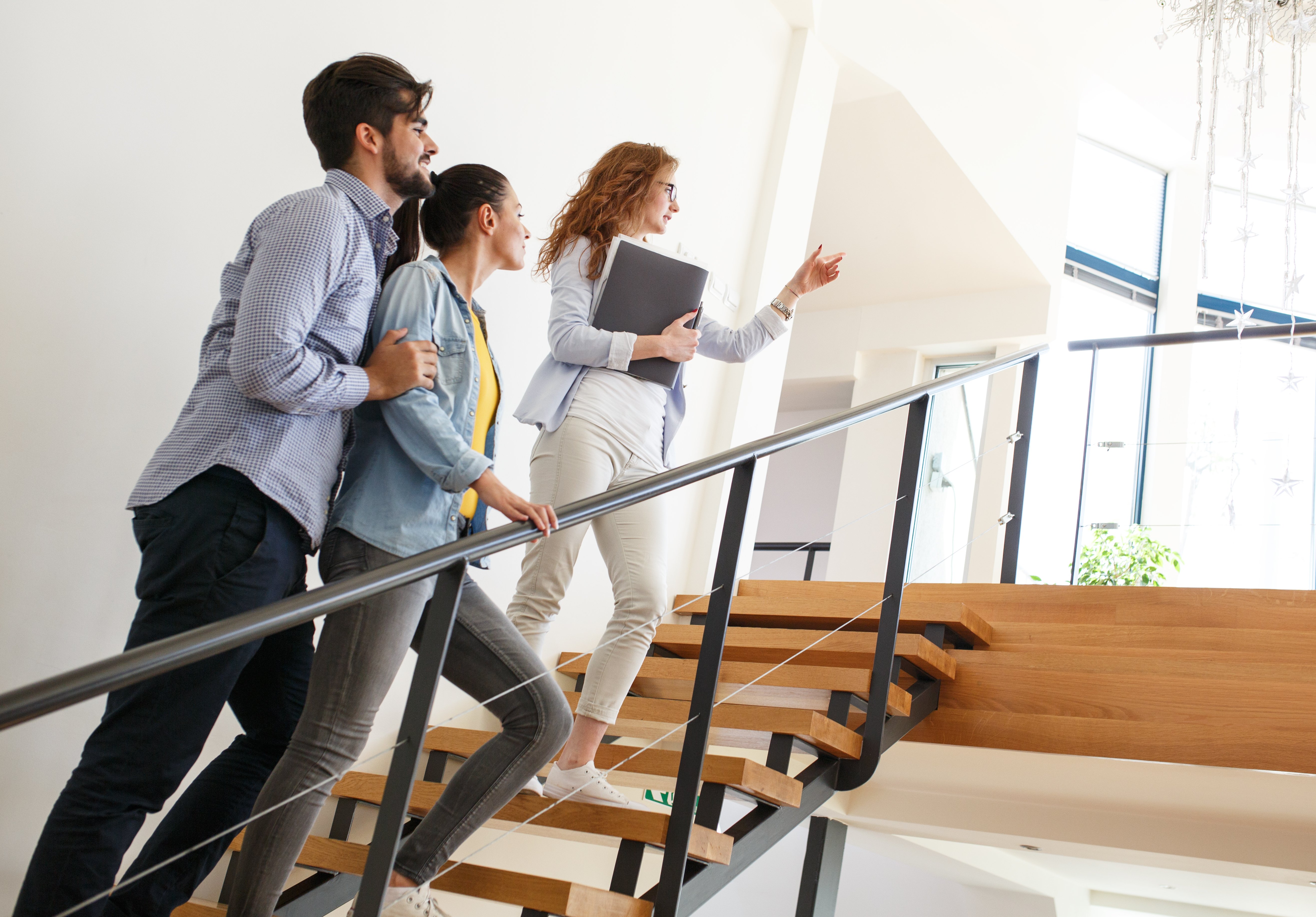 Canva - Female Real Estate agent shows interior to young couple.